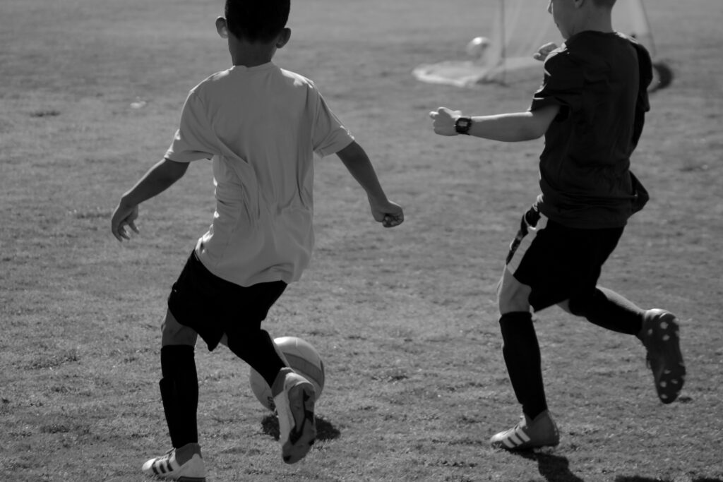 Two boys playing soccer on field