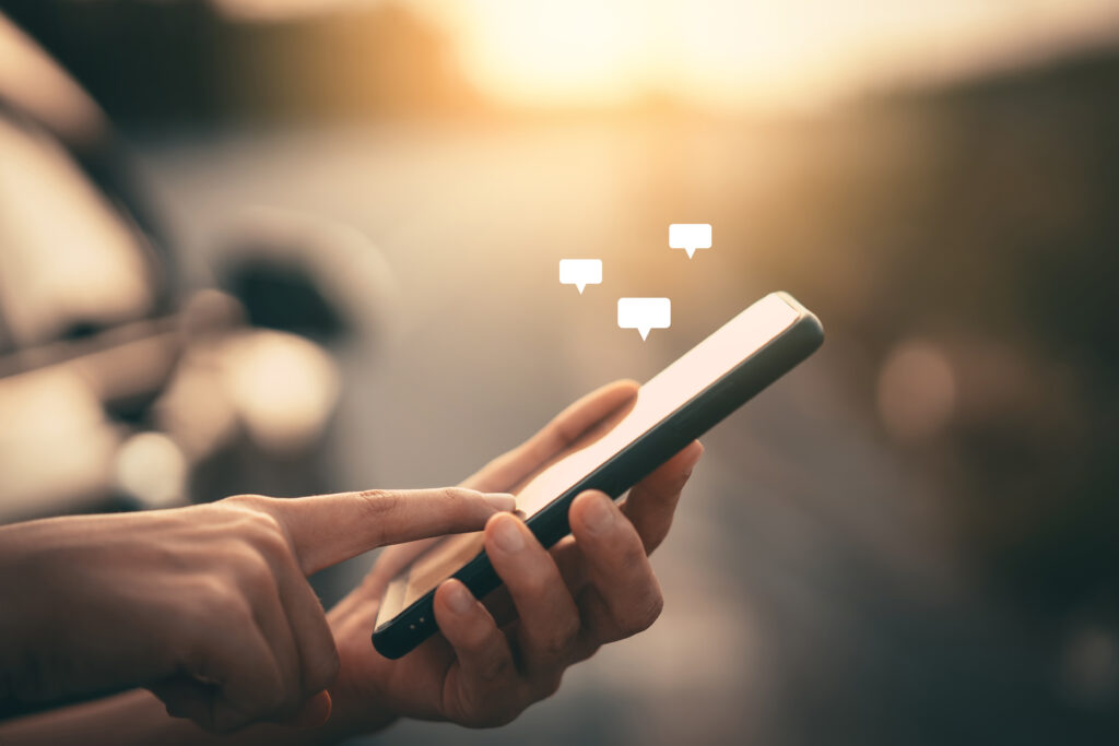 A person holding a smartphone with three floating speech bubble icons above the screen.